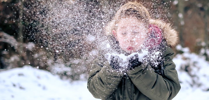 Enfant qui souffle sur la neige posée sur ses mains