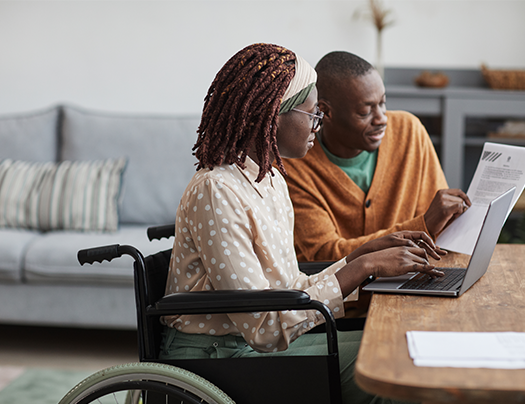  Personne en fauteuil roulant accompagnée par un professionnel devant un écran