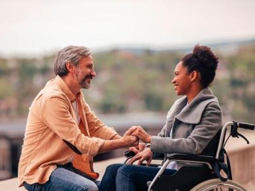 une femme en fauteuil roulant tien t la main de son compagnon