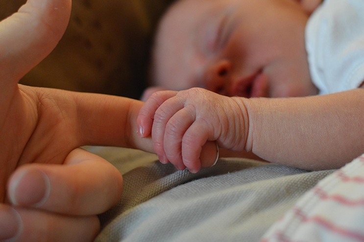 un bebe qui dort et qui tient la main d'un adulte