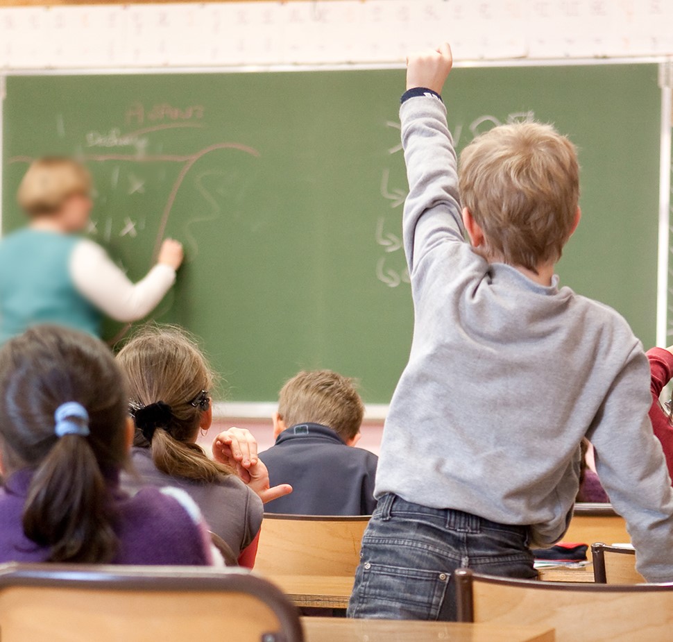 enfant levant la main dans une classe