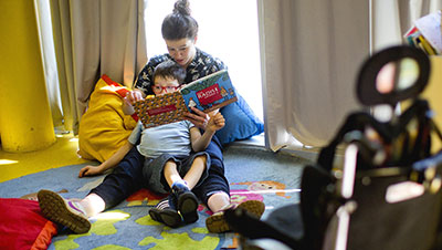 une maman lit une histoire à son enfant en situation de handicap