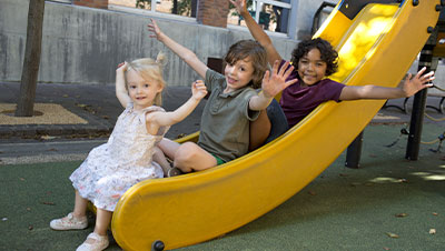 trois enfants qui jouent sur un toboggan