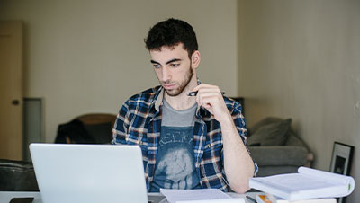 Homme habillé de manière détendu devant son ordinateur, dans son salon