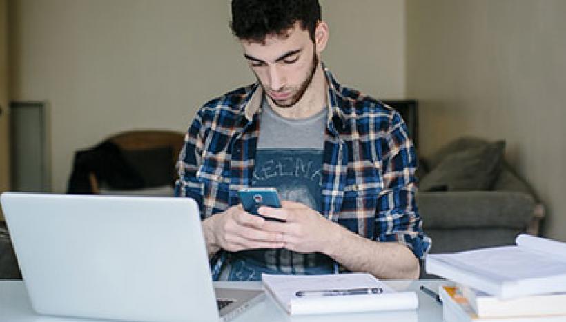 un homme sur son téléphone et son ordinateur pour le travail